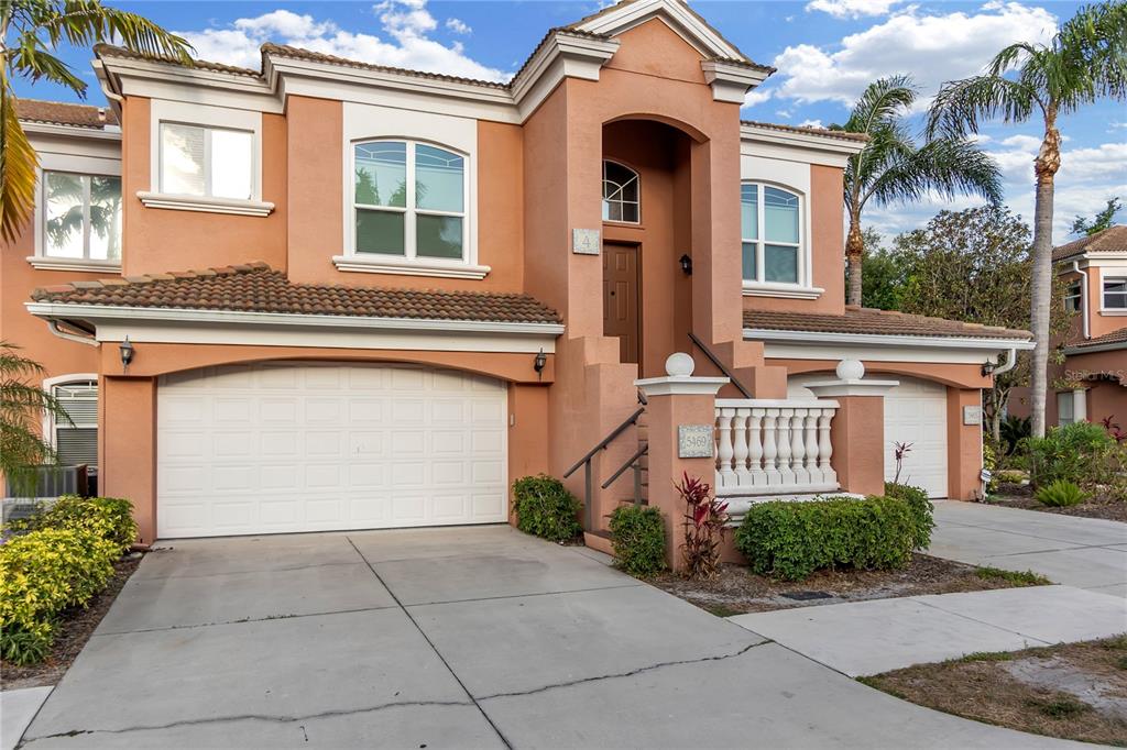 A two-story stucco house features a two-car garage, a raised entryway, and palm trees — 5469 46TH COURT W, BRADENTON, FL