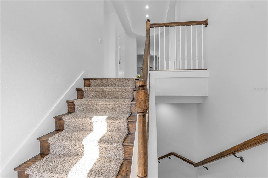 A staircase with carpeted treads and a wooden handrail leads to an upper landing — 5469 46TH COURT W, BRADENTON, FL