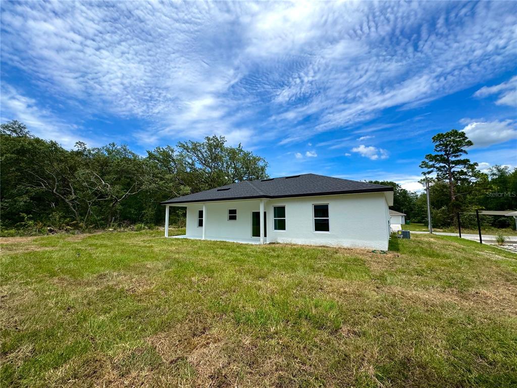 The exterior of a white, single-story house with a dark roof sits on a grassy lot — 8210 N BROOK WAY, CITRUS SPRINGS, FL