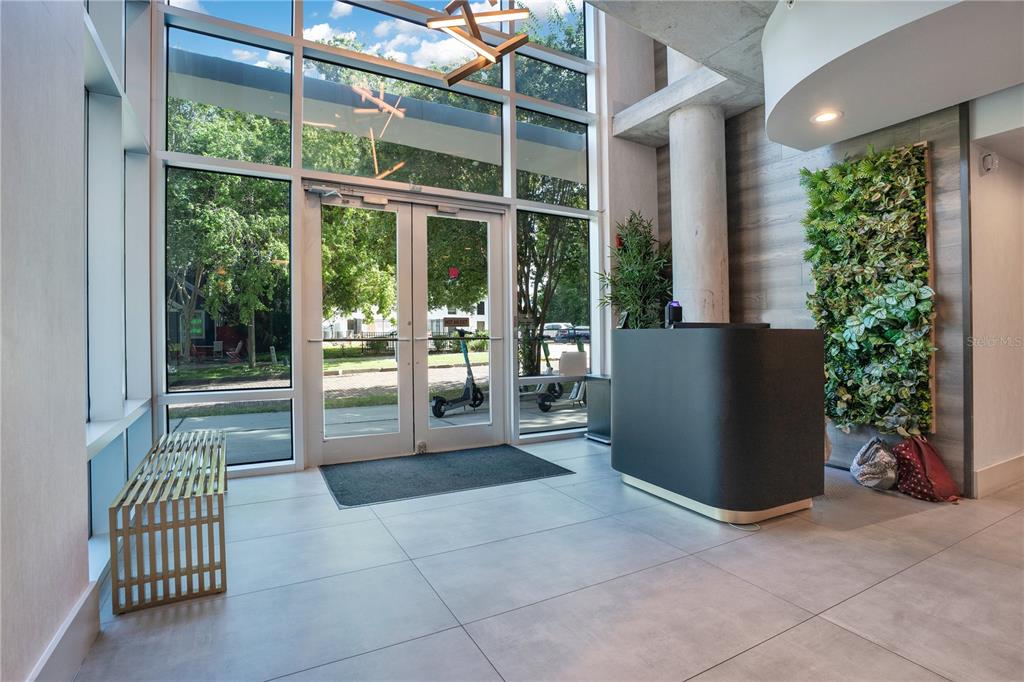 A modern lobby features a reception desk, a vertical garden wall, and floor-to-ceiling windows — 525 E JACKSON STREET UNIT 509, ORLANDO, FL