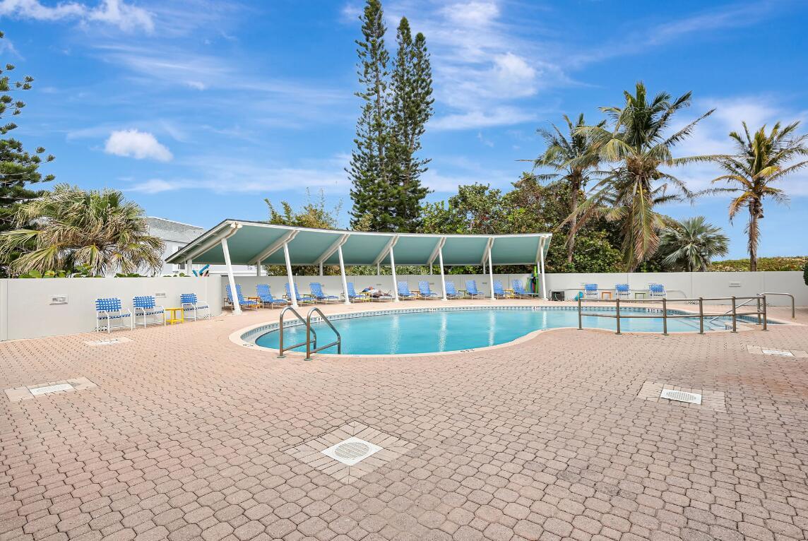 An outdoor swimming pool with a covered patio area and lounge chairs on a brick deck — 1357 NE Ocean Boulevard # 311, Stuart FL 34996, STUART, FL