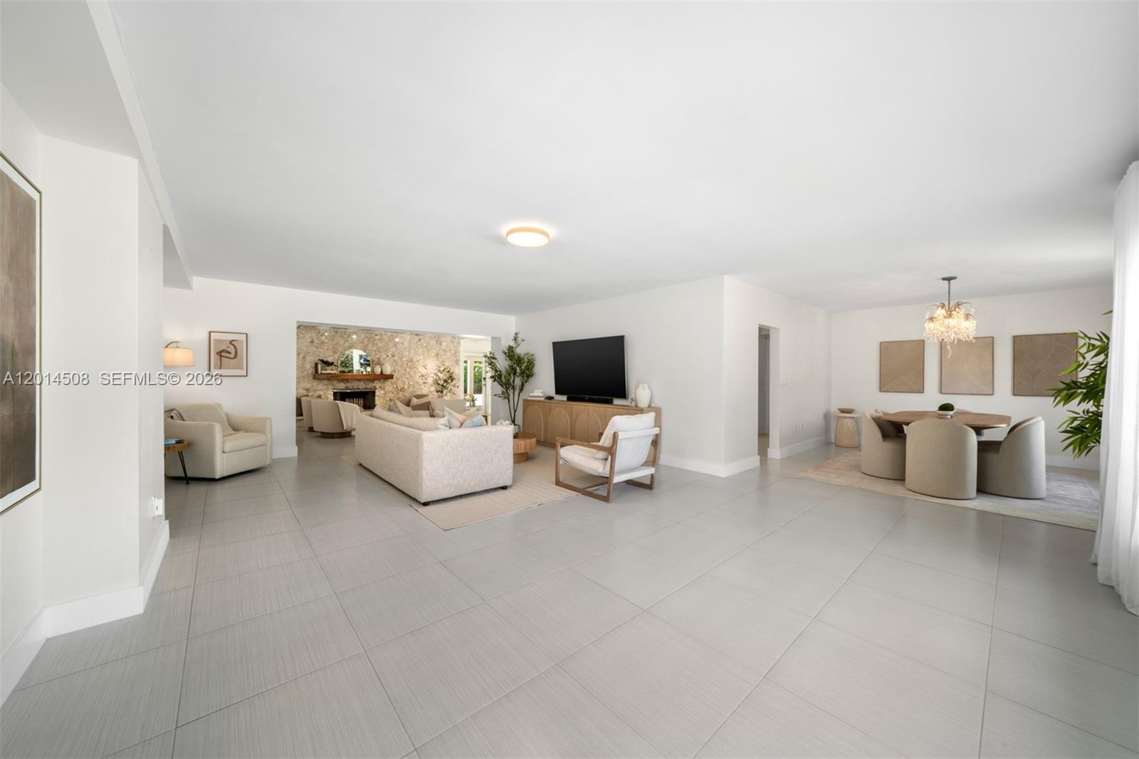 A spacious living and dining area features white walls, large light-colored floor tiles, and furniture — 6450 SW 128th St, Pinecrest FL 33156, PINECREST, FL