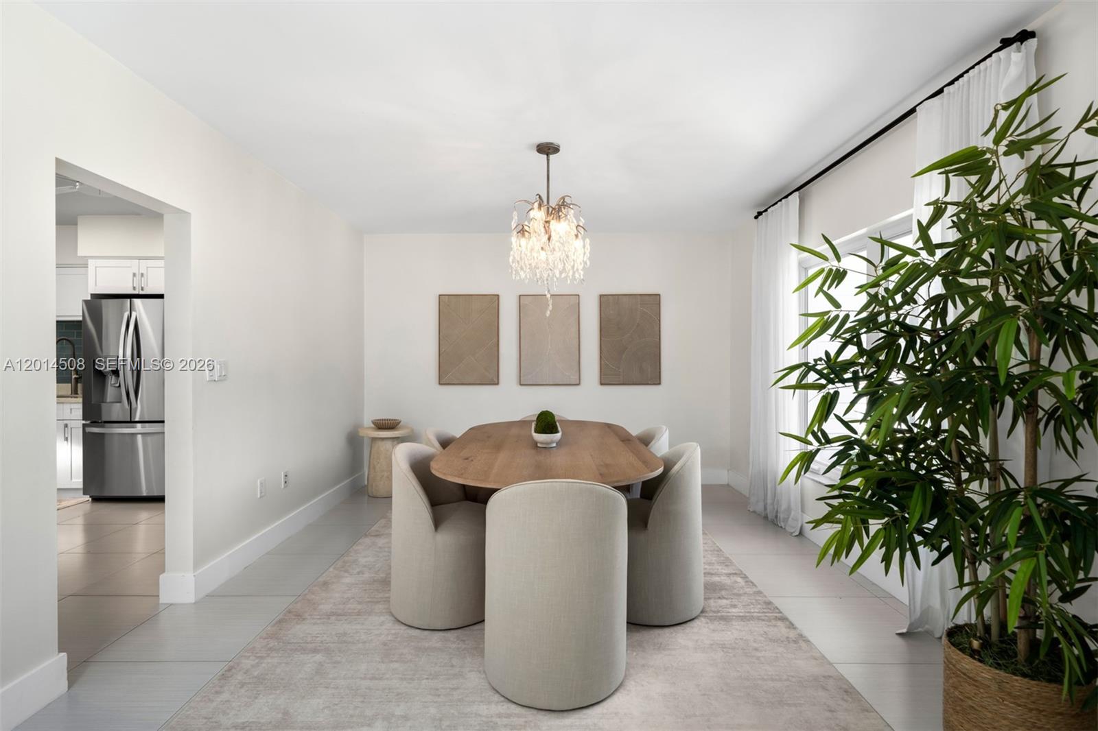 A dining room features an oval wooden table, upholstered chairs, a crystal chandelier, and artwork — 6450 SW 128th St, Pinecrest FL 33156, PINECREST, FL