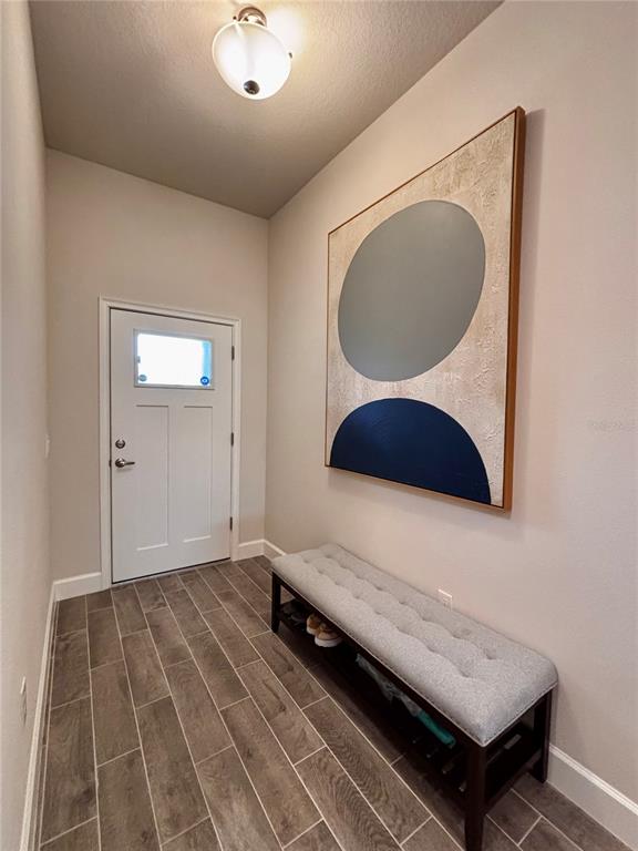 An entryway features wood-look tile flooring, a tufted bench, and a large abstract wall painting — 11801 SUNDER BERRY STREET, HUDSON, FL