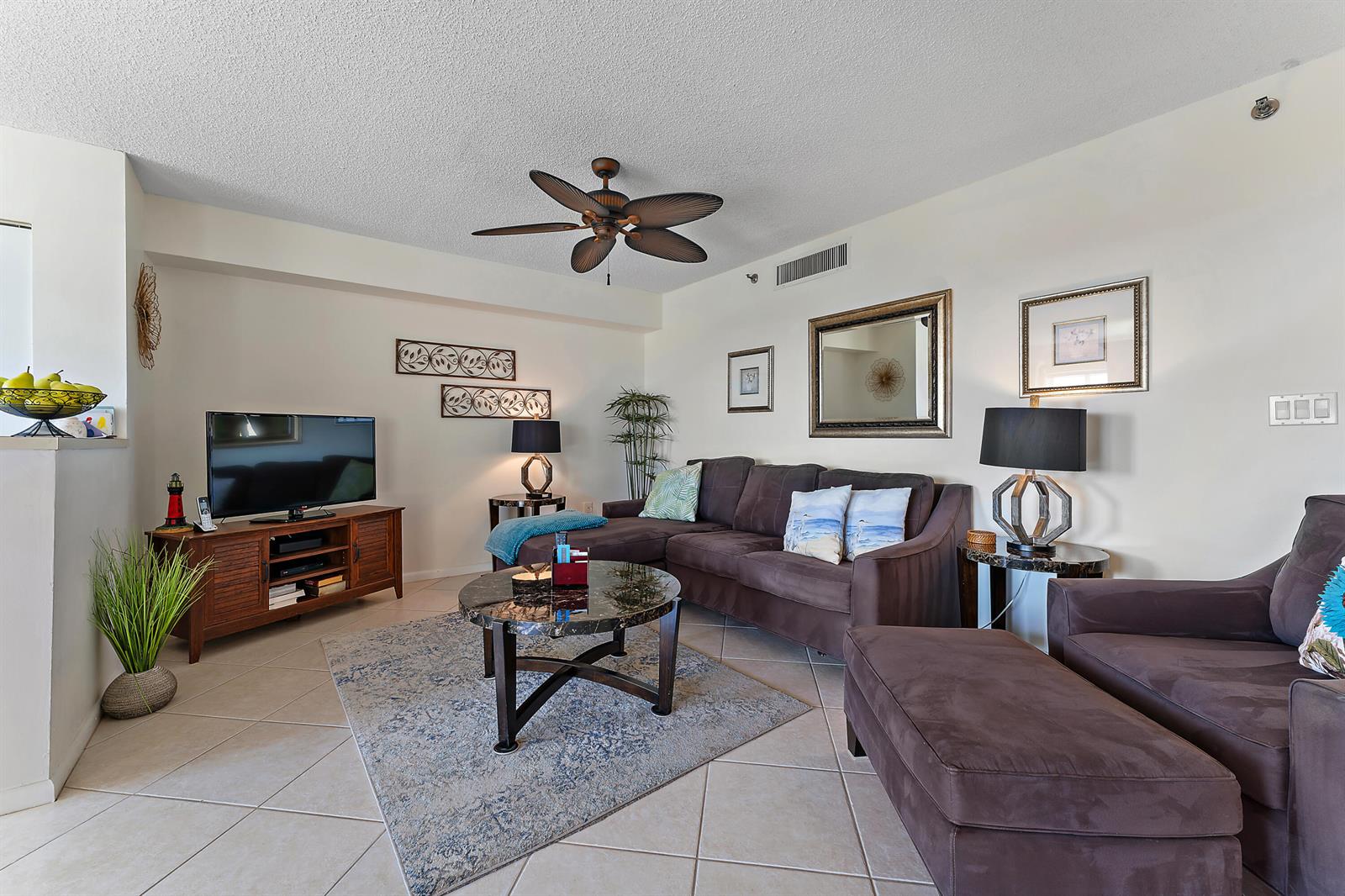 A living room features a brown sectional sofa, a coffee table, and a television console — 275 Palm Avenue # C503, Jupiter FL 33477, JUPITER, FL