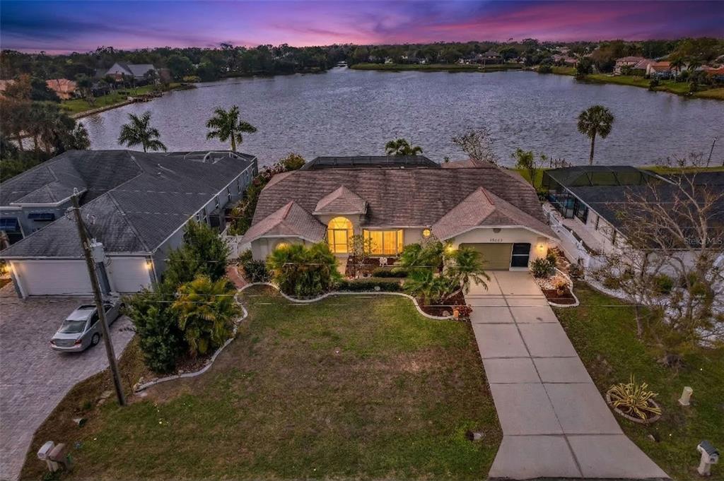 An aerial view of a single-story house with a lakefront backyard and paved driveway — 23439 FREEPORT AVENUE, PORT CHARLOTTE, FL