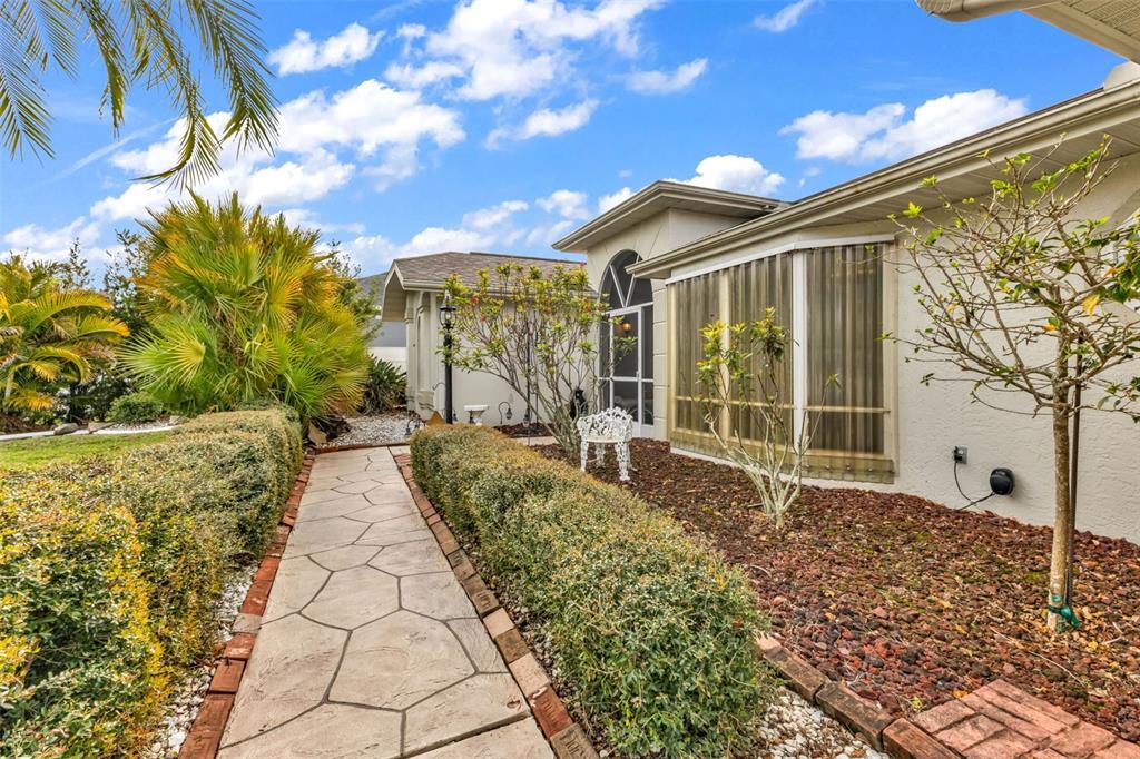 A stone walkway leads toward the entrance of a house with a landscaped front yard — 23439 FREEPORT AVENUE, PORT CHARLOTTE, FL
