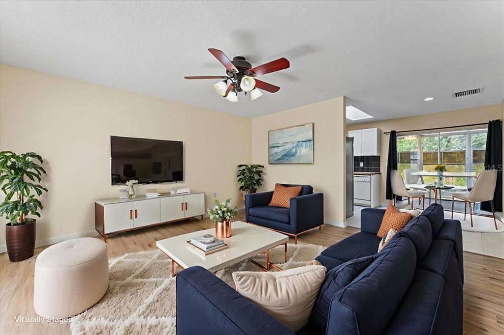 A living room with a navy sofa, armchair, white coffee table, and a wall-mounted television — 3701 MODESTO STREET, NEW PORT RICHEY, FL