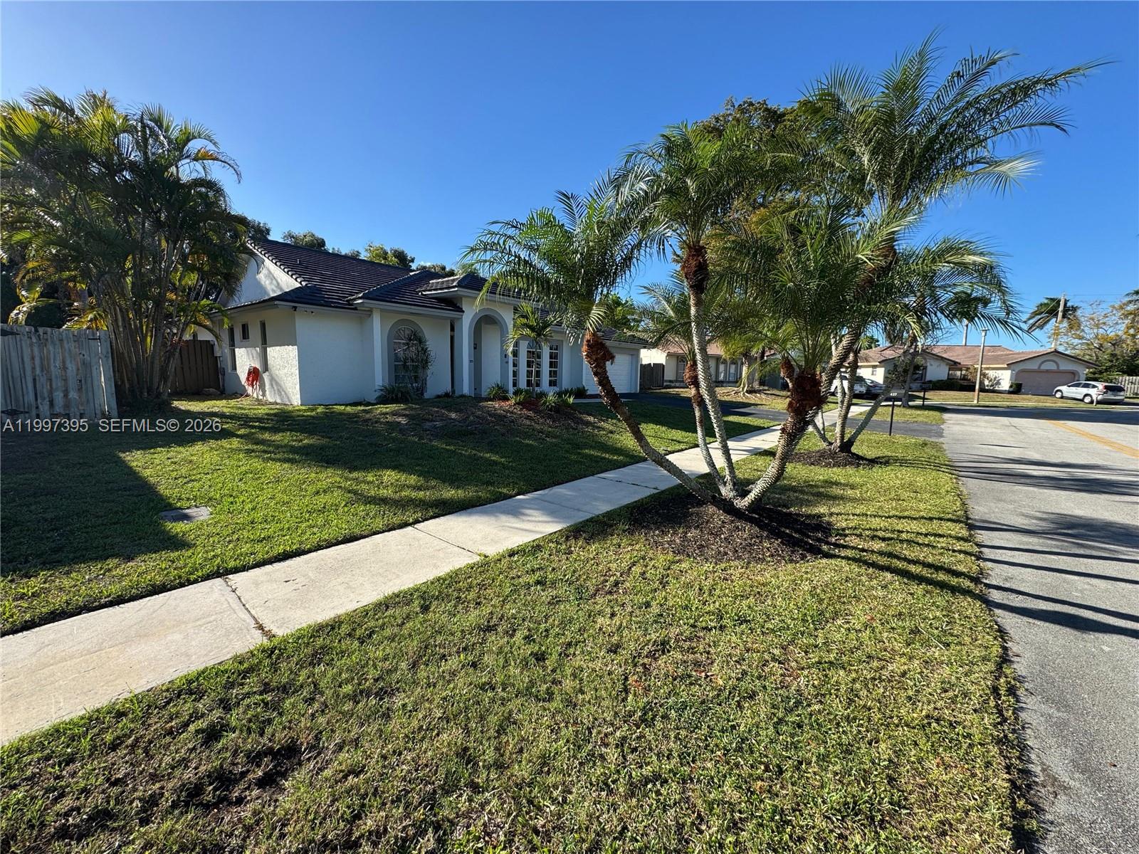 A white single-story house with a tiled roof sits behind a lawn and palm trees — 427 SW 169th Ter, Weston FL 33326, WESTON, FL