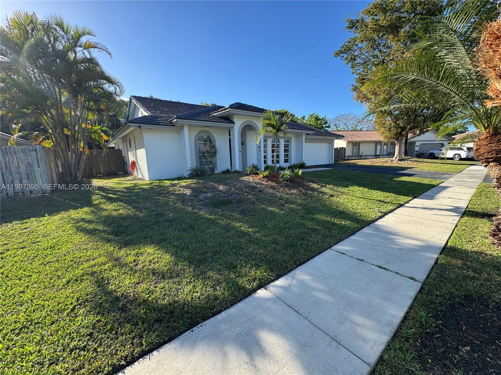 A single-story white house with a dark tiled roof and a front lawn — 427 SW 169th Ter, Weston FL 33326, WESTON, FL