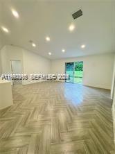 An empty room features light-colored wood-look flooring in a herringbone pattern and recessed ceiling lights — 427 SW 169th Ter, Weston FL 33326, WESTON, FL