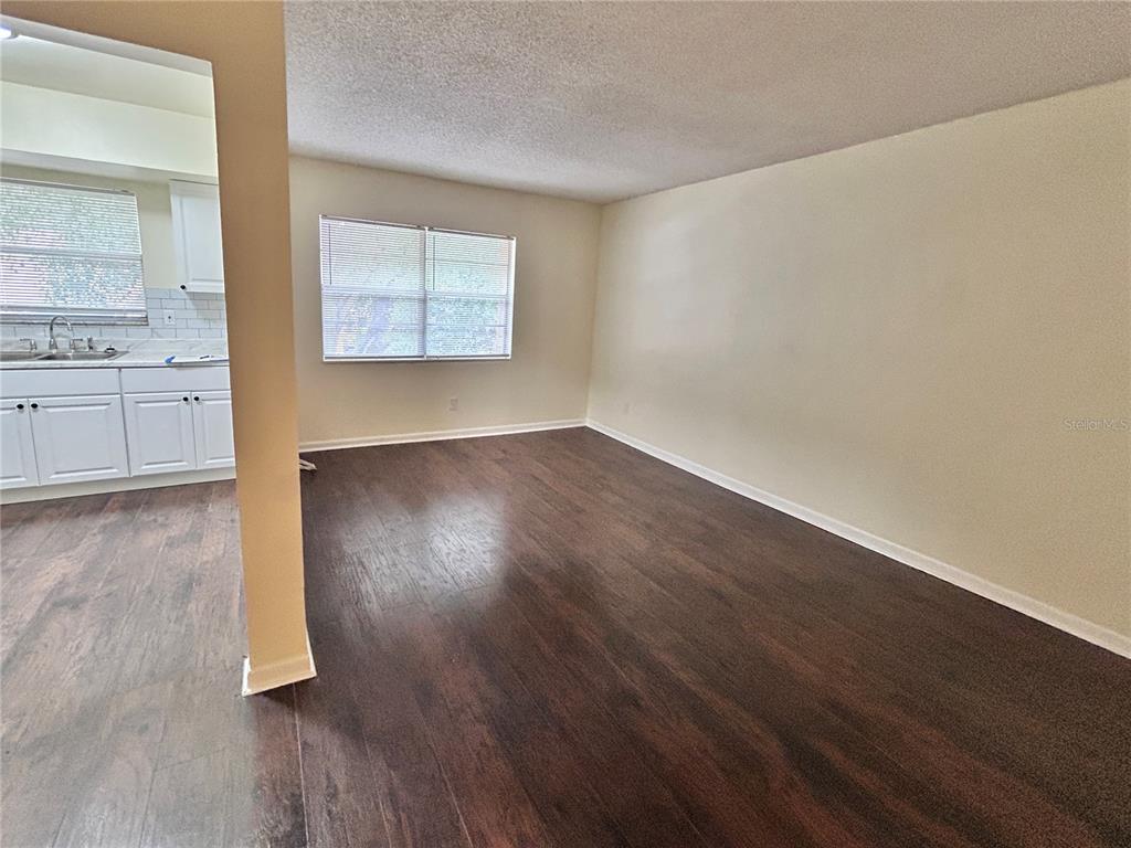 A living room with dark wood-look flooring and a view into an adjacent white kitchen — 4455 38TH TERRACE N UNIT B16, ST PETERSBURG, FL