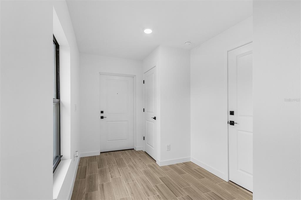 A bright entryway with white walls, wood-look tile flooring, and two interior doors — 4743 MICHALER STREET, NORTH PORT, FL