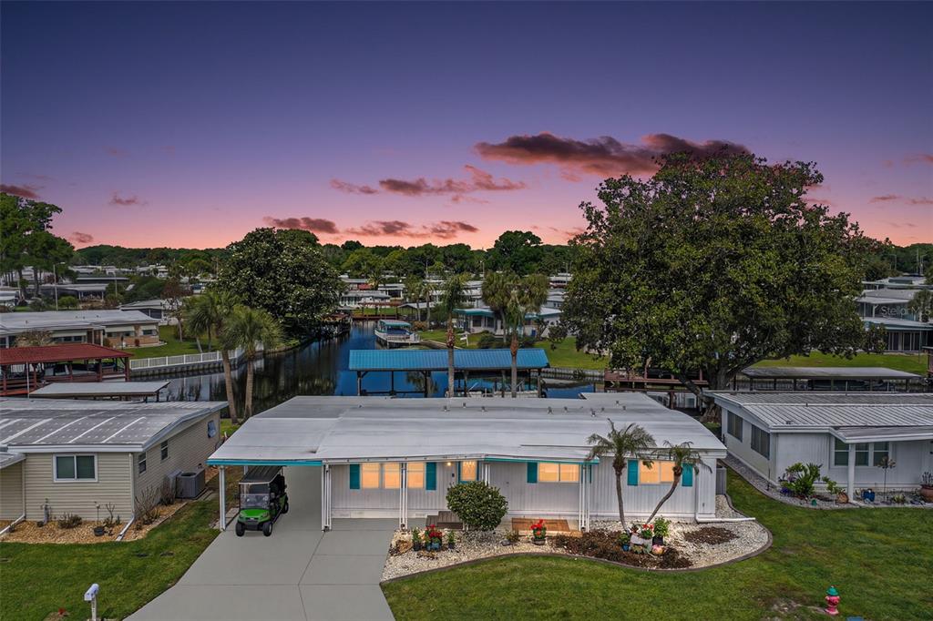 An aerial view of a single-story mobile home with a carport and canal access — 1015 SOUTHLAND DRIVE, TAVARES, FL