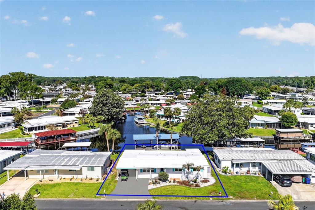 An aerial view shows a white single-story house with a carport and a backyard canal — 1015 SOUTHLAND DRIVE, TAVARES, FL