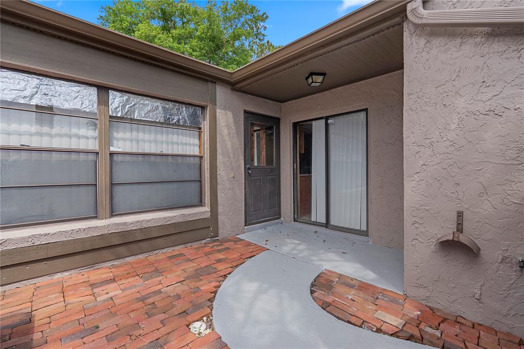 A small patio features a brick floor, a concrete walkway, and two exterior doors — 497 MEADOWOOD BOULEVARD, FERN PARK, FL