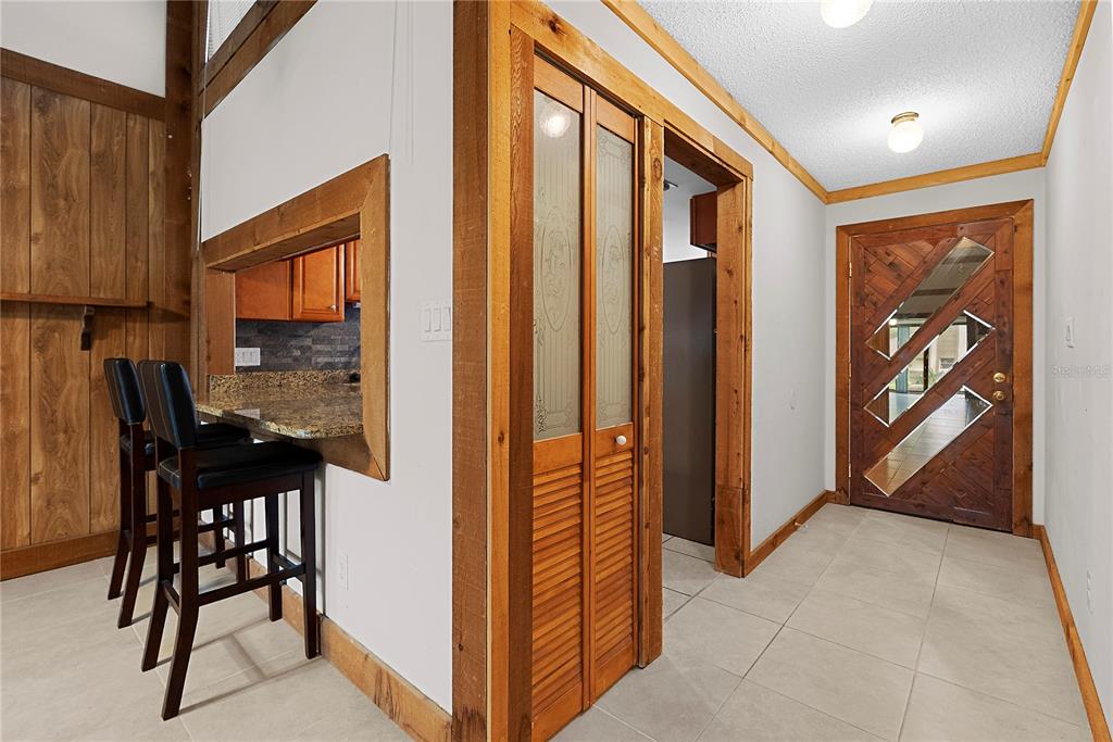 An interior view shows a kitchen pass-through, a louvered closet door, and a decorative wooden door — 497 MEADOWOOD BOULEVARD, FERN PARK, FL