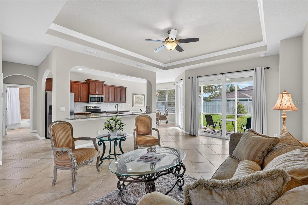 A living room with tile floors, a ceiling fan, and an open view of the kitchen — 123 ARENA LAKE DRIVE, PALM COAST, FL