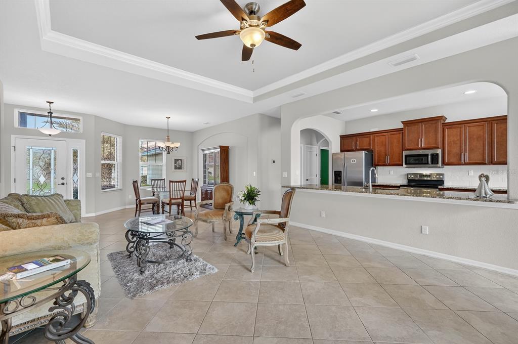 A living room with tile floors and a ceiling fan opens to a kitchen area — 123 ARENA LAKE DRIVE, PALM COAST, FL