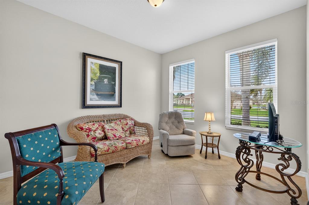 A living room features tile flooring, a wicker sofa, a teal armchair, and two windows — 123 ARENA LAKE DRIVE, PALM COAST, FL
