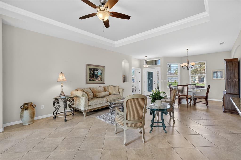 A spacious living and dining area with tile floors, a tray ceiling, and ceiling fan — 123 ARENA LAKE DRIVE, PALM COAST, FL
