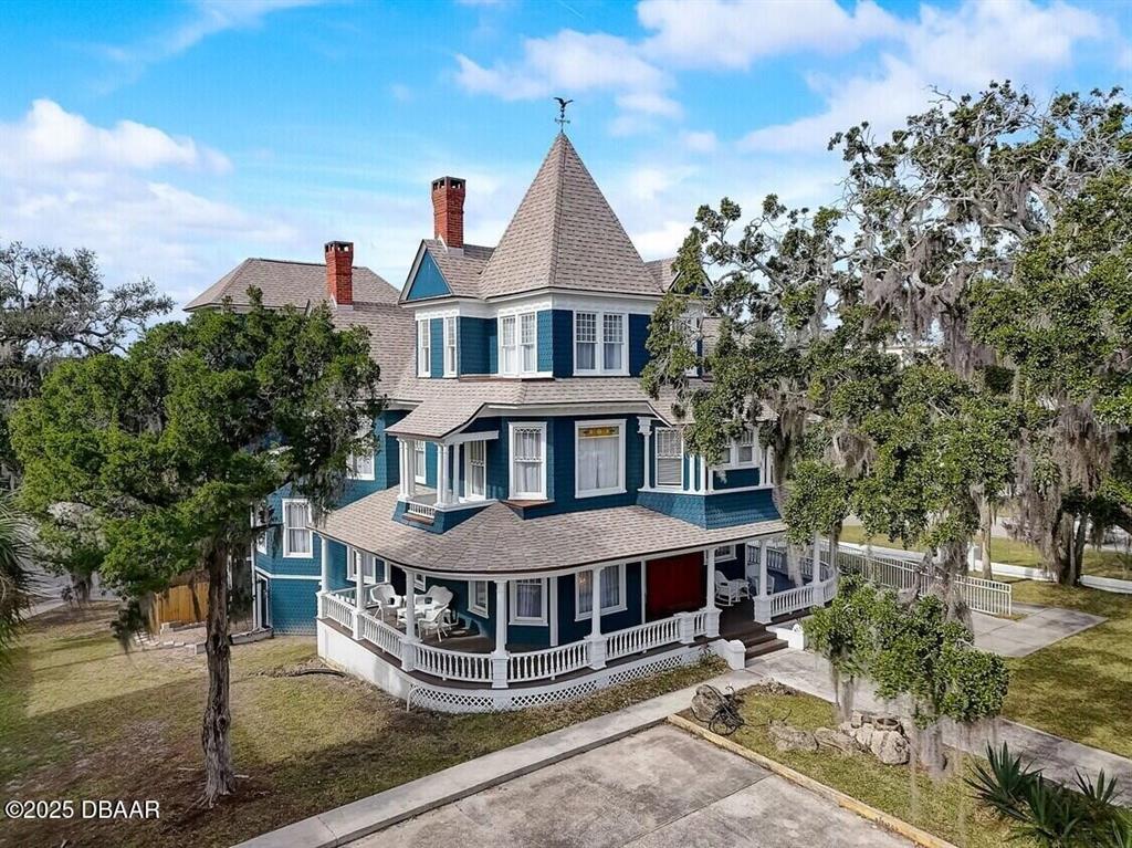 An aerial view of a blue Victorian-style house with a wraparound porch and corner turret — 404 S RIDGEWOOD AVENUE, DAYTONA BEACH, FL