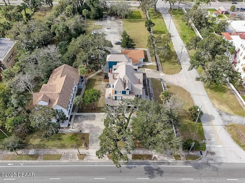 An aerial view shows two large buildings situated on a lot with trees and pavement — 404 S RIDGEWOOD AVENUE, DAYTONA BEACH, FL