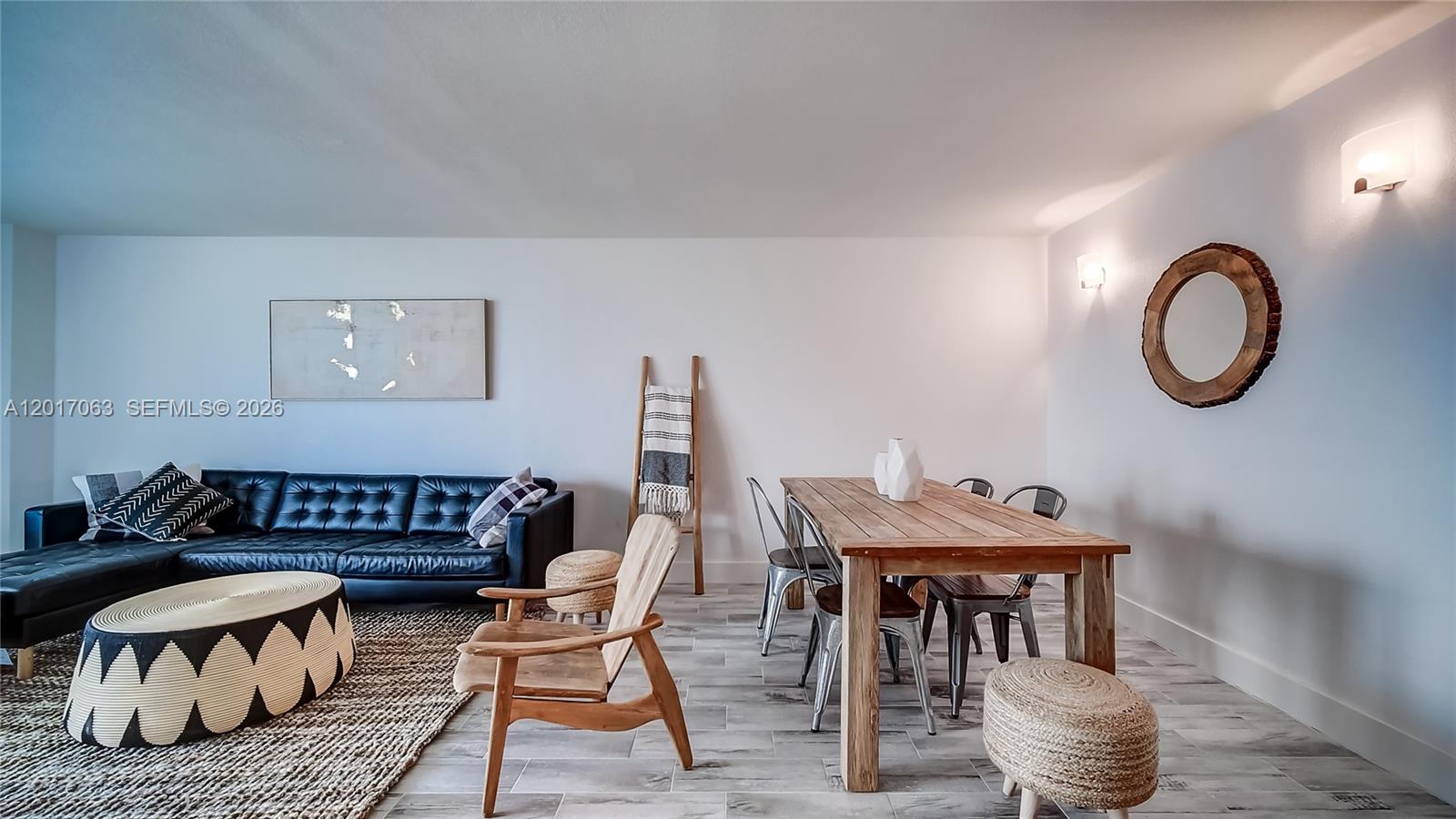 A living and dining area features a black leather sofa, wooden table, and tiled floors — MIAMI BEACH, FL