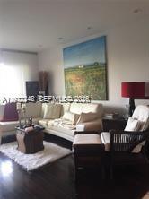 A living room features a beige sectional sofa, a dark wood side table, and wall art — 2451 Brickell Ave # 4P, Miami FL 33129, MIAMI, FL