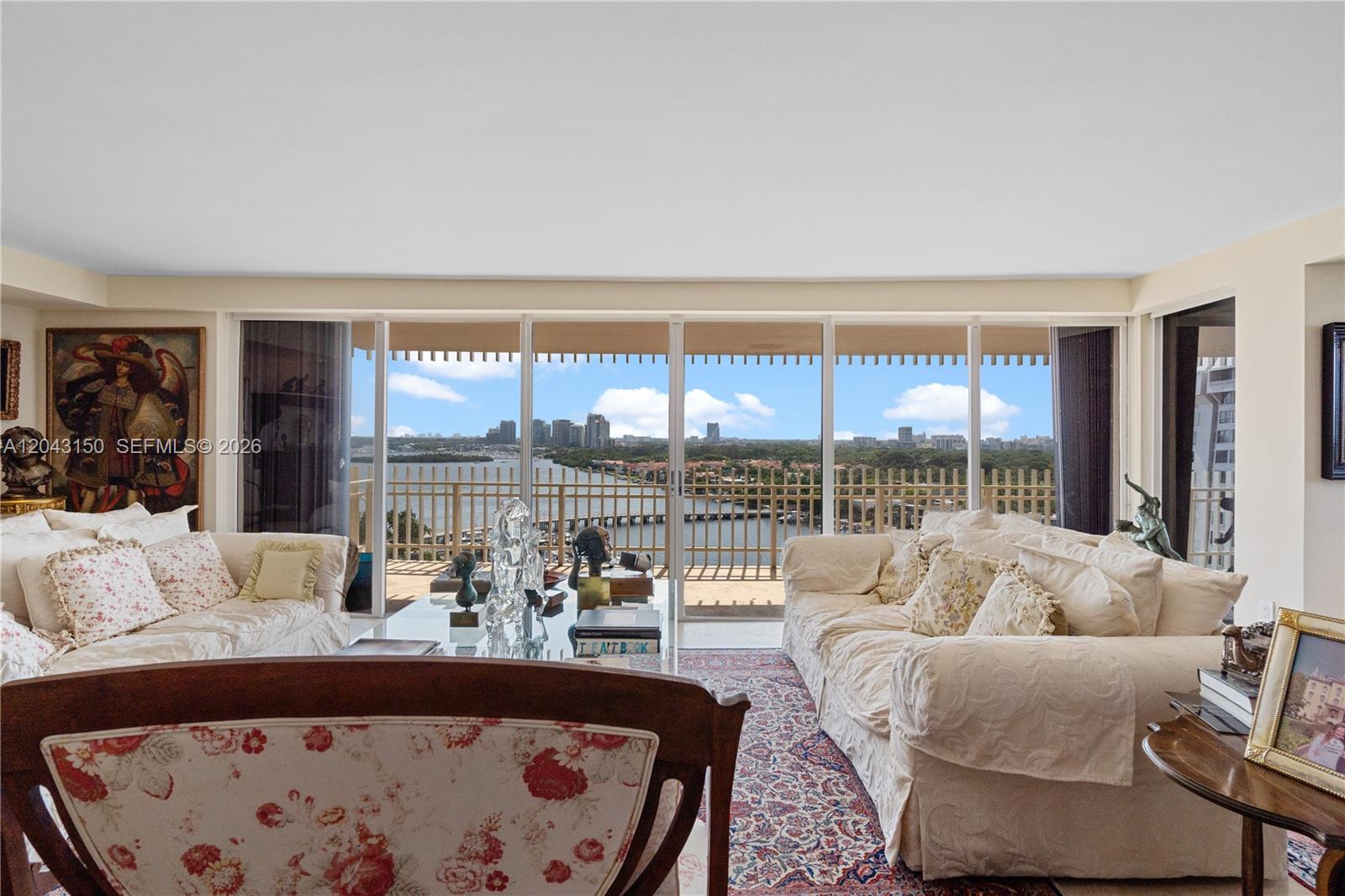 A living room features two white sofas, a patterned rug, and floor-to-ceiling windows overlooking water — 3 Grove Isle Dr # C1610, Miami FL 33133, MIAMI, FL