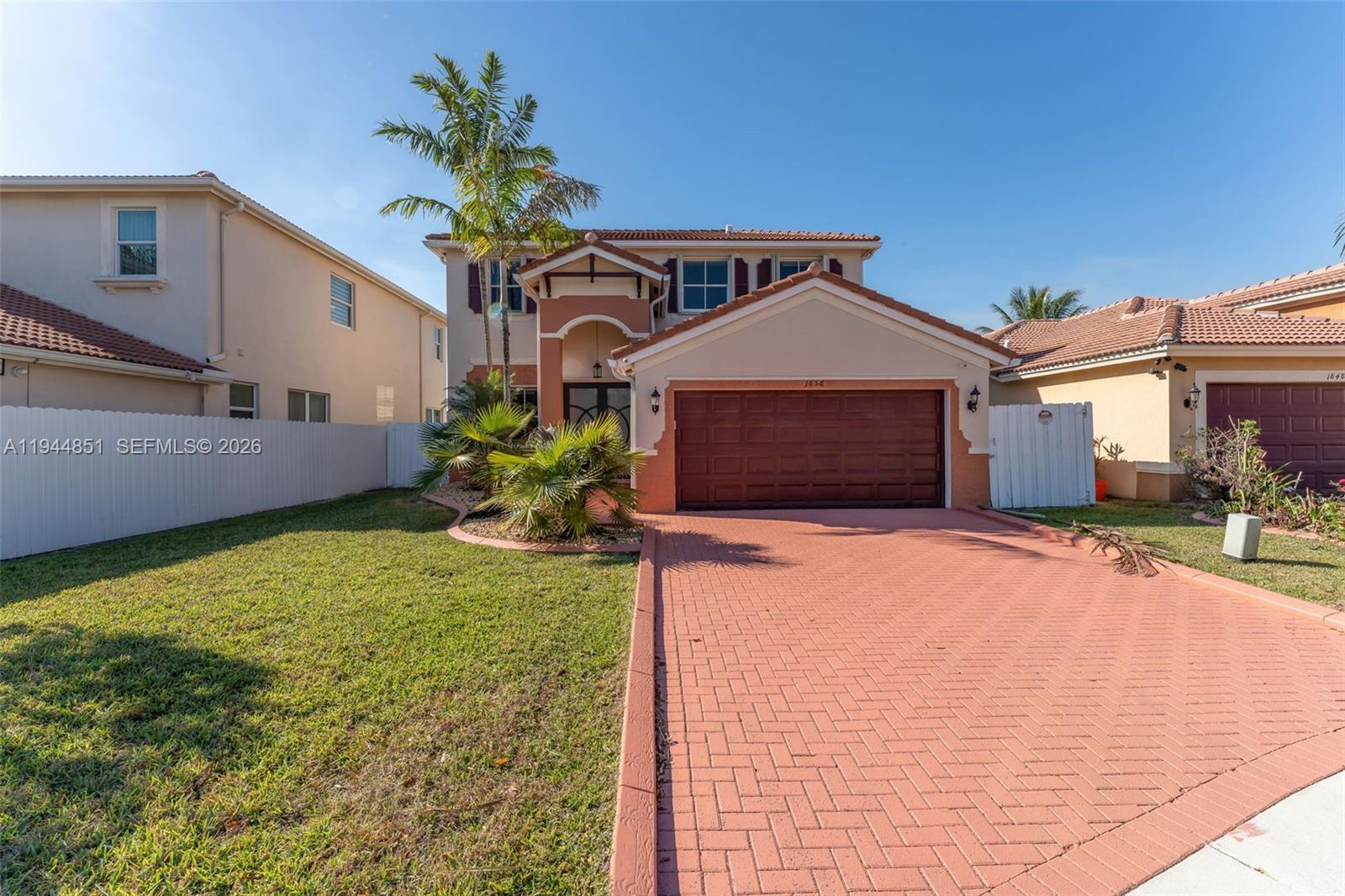 A two-story house features a red brick driveway, a garage, and a palm tree — 1856 NE 3rd Ct, Homestead FL 33033, HOMESTEAD, FL