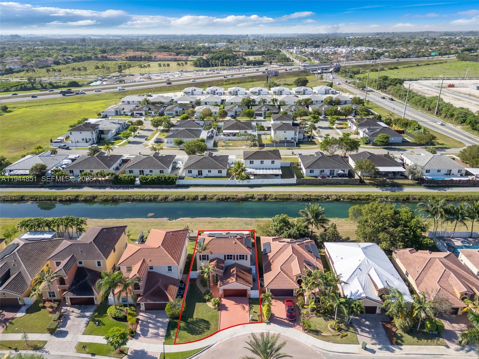 An aerial view shows a residential neighborhood with a highlighted house facing a canal — 1856 NE 3rd Ct, Homestead FL 33033, HOMESTEAD, FL