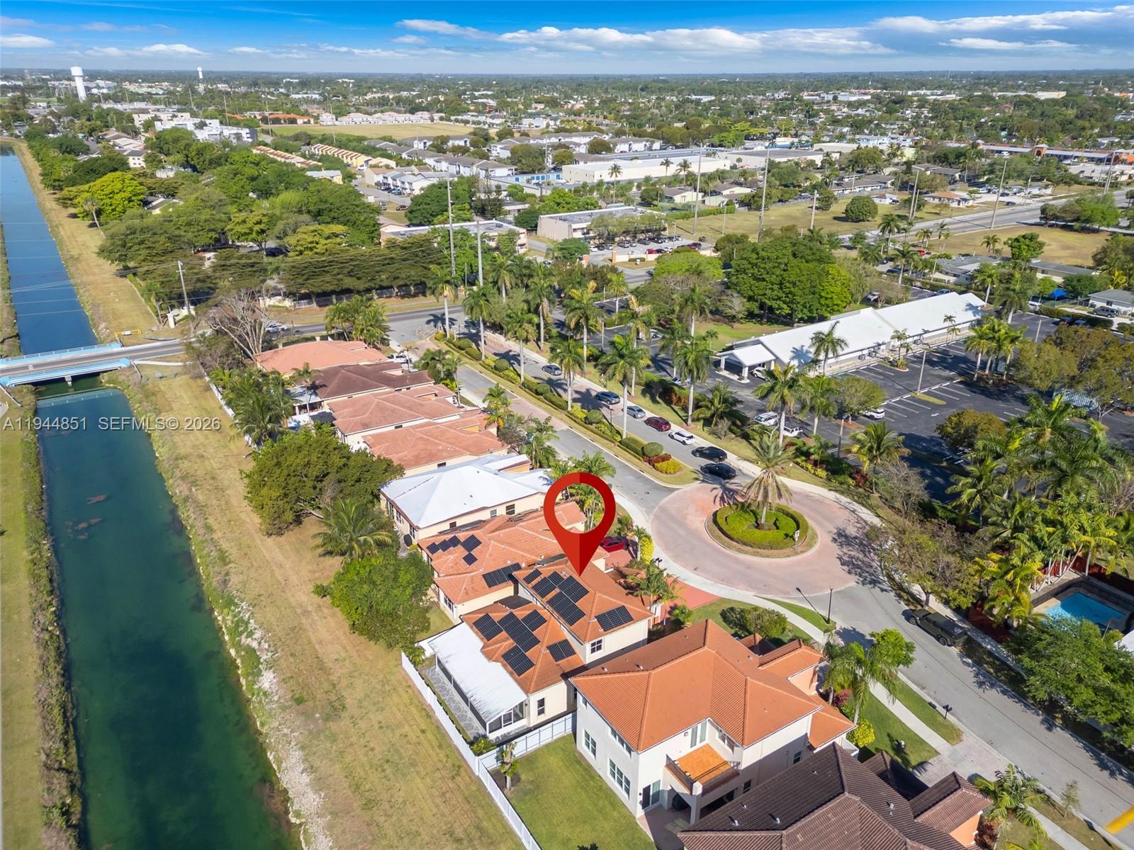 An aerial view shows a residential neighborhood with a canal and solar-paneled rooftops — 1856 NE 3rd Ct, Homestead FL 33033, HOMESTEAD, FL
