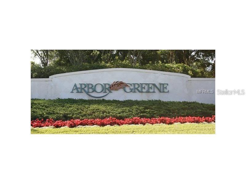 A stone monument sign for Arbor Greene sits behind a bed of red flowers — 10144 ARBOR RUN DRIVE UNIT 89, TAMPA, FL