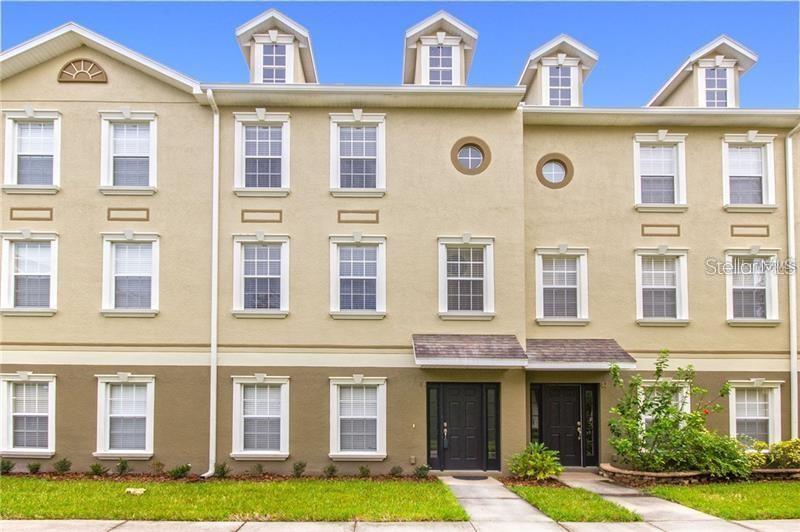 A multi-story tan townhouse exterior with dark doors, white-trimmed windows, and four roof dormers — 10144 ARBOR RUN DRIVE UNIT 89, TAMPA, FL