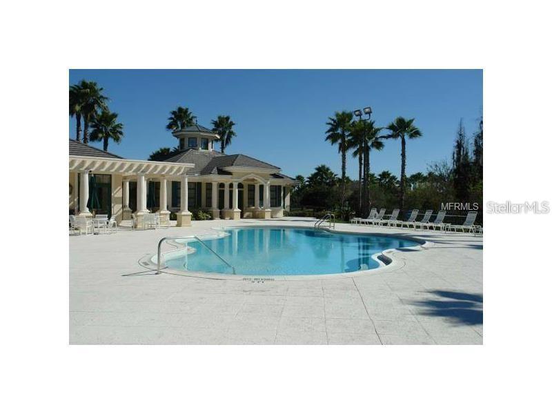 A swimming pool sits on a patio in front of a clubhouse with palm trees — 10144 ARBOR RUN DRIVE UNIT 89, TAMPA, FL