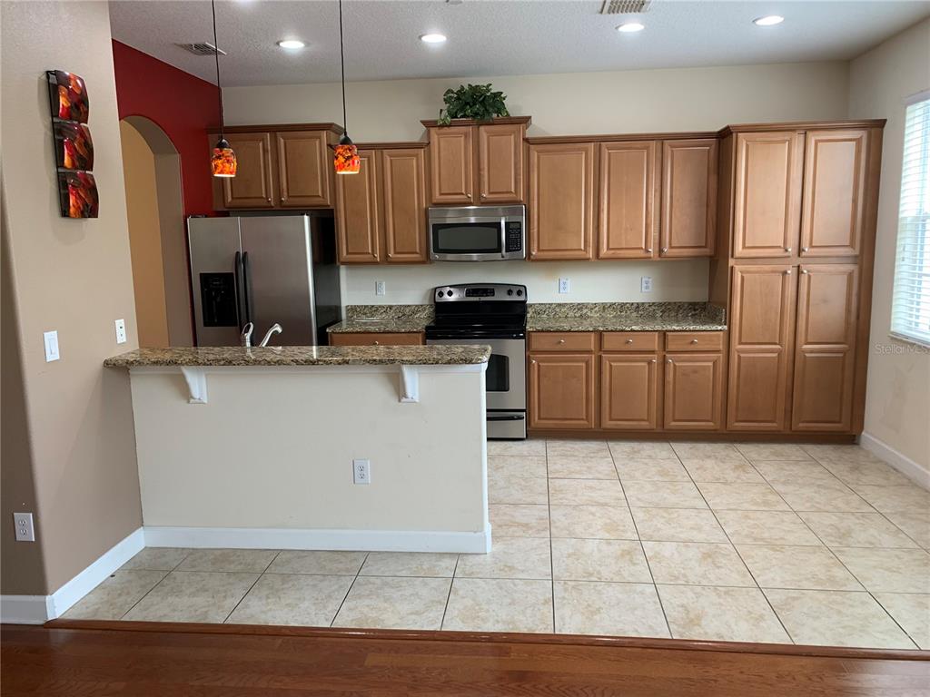 A kitchen features wood cabinets, granite countertops, stainless steel appliances, and tile flooring — 10144 ARBOR RUN DRIVE UNIT 89, TAMPA, FL