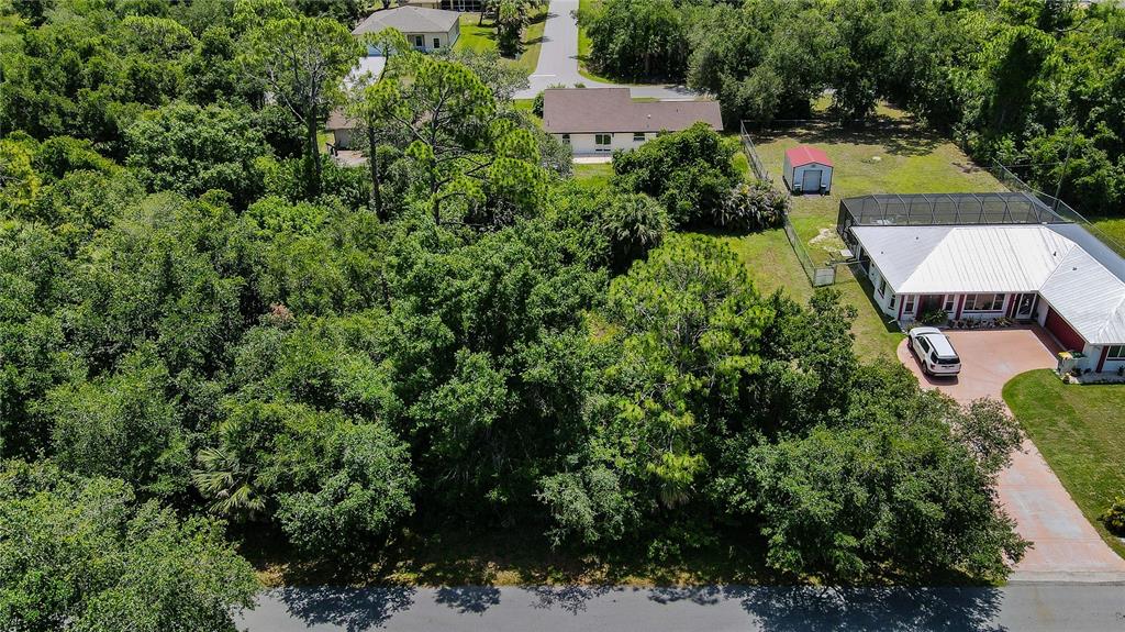 An aerial view shows a wooded vacant lot situated between two residential properties — 3388 HAMPTON STREET, PORT CHARLOTTE, FL