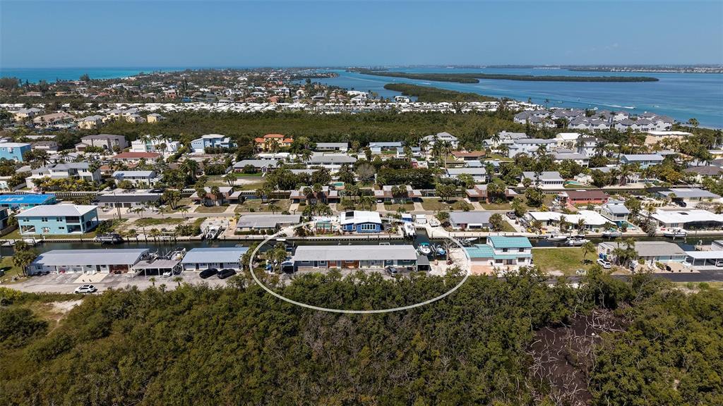 An aerial view shows a long, single-story building surrounded by dense vegetation and waterfront homes — 729 SAINT JUDES DRIVE S UNIT 3, LONGBOAT KEY, FL