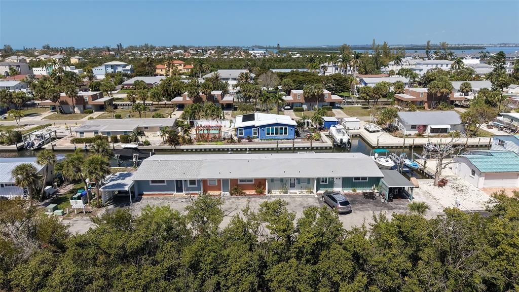 An aerial view shows a single-story multi-unit building with a parking area and canal access — 729 SAINT JUDES DRIVE S UNIT 3, LONGBOAT KEY, FL