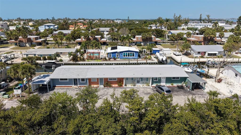 An aerial view shows a multi-unit residential building with a parking lot and canal access — 729 SAINT JUDES DRIVE S UNIT 3, LONGBOAT KEY, FL