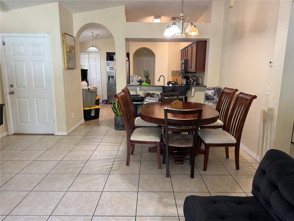 A dining area with a round wooden table and chairs sits adjacent to an open kitchen — 18250 SNOWDONIA DRIVE, LAND O LAKES, FL