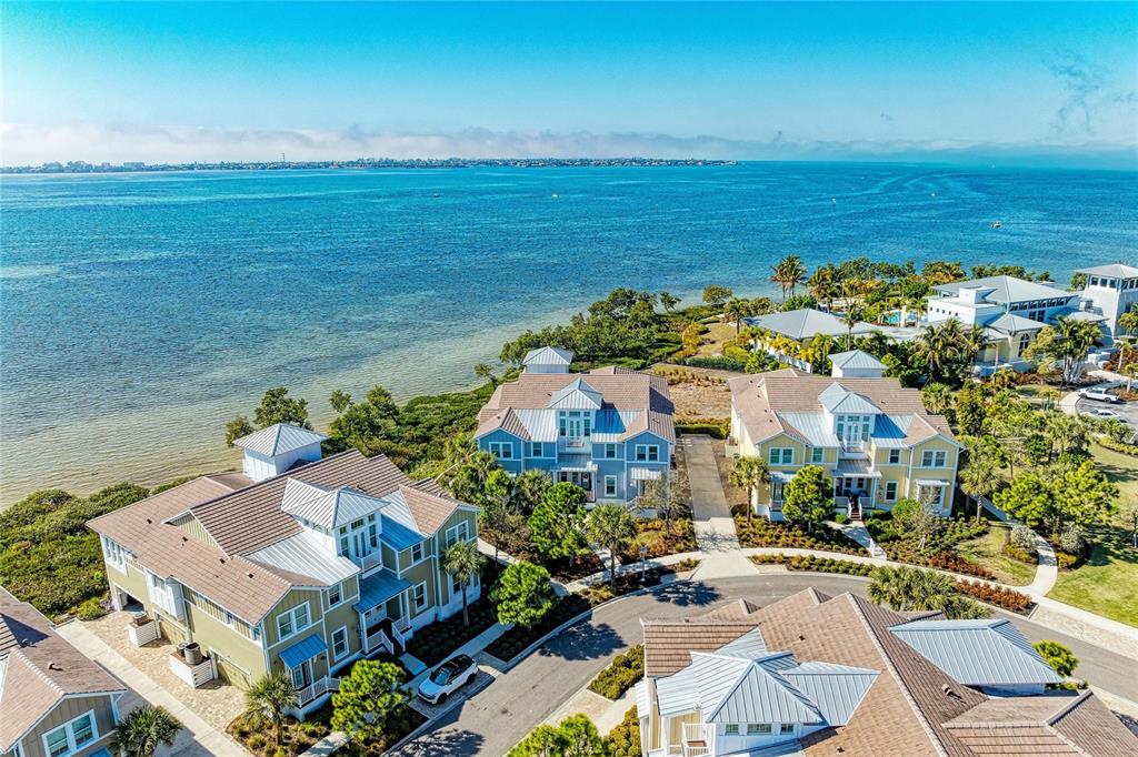 An aerial view shows several multi-story coastal houses situated along a waterfront with lush landscaping — 268 SAINT LUCIA DRIVE UNIT 101, BRADENTON, FL