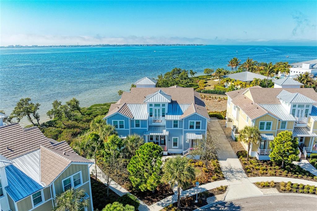 An aerial view shows a blue coastal house with a metal roof near the water — 268 SAINT LUCIA DRIVE UNIT 101, BRADENTON, FL