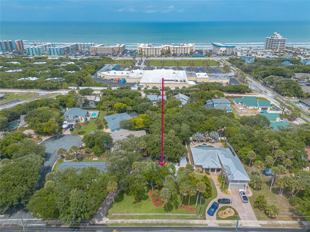 An aerial view shows a residential property with a large yard and nearby beach buildings — 4181 SAXON DRIVE, NEW SMYRNA BEACH, FL