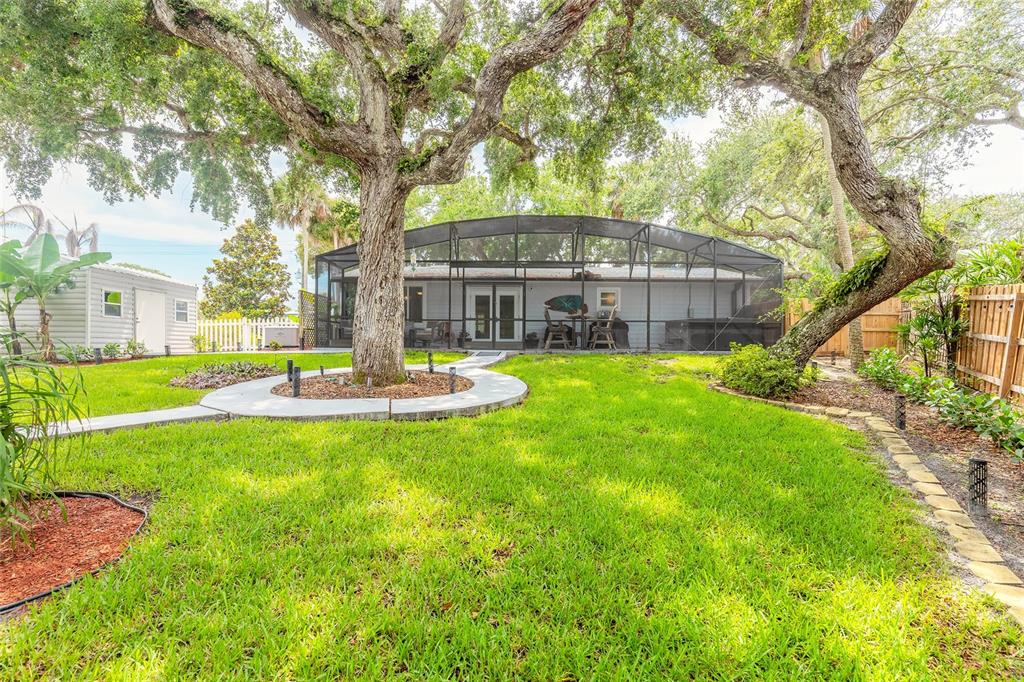 A backyard features a screened-in patio, large oak trees, and a small detached storage shed — 4181 SAXON DRIVE, NEW SMYRNA BEACH, FL