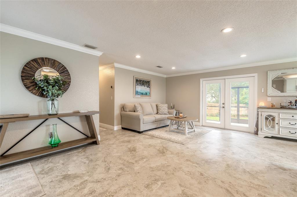 A living room features light tile floors, a neutral sofa, a console table, and French doors — 4181 SAXON DRIVE, NEW SMYRNA BEACH, FL