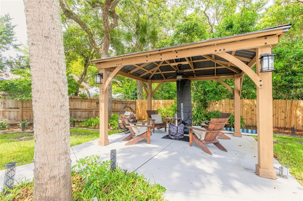 A wooden gazebo with a metal roof sits on a concrete patio in a backyard — 4181 SAXON DRIVE, NEW SMYRNA BEACH, FL