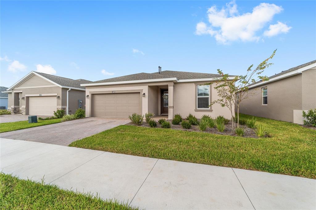 A single-story tan house with a two-car garage and a paved driveway — 5521 NW 45TH LANE, OCALA, FL