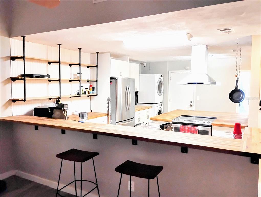A kitchen features a wooden breakfast bar, open industrial shelving, and stainless steel appliances — 2012 DOVER COURT, OLDSMAR, FL